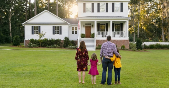 Family from behind standing outside their house